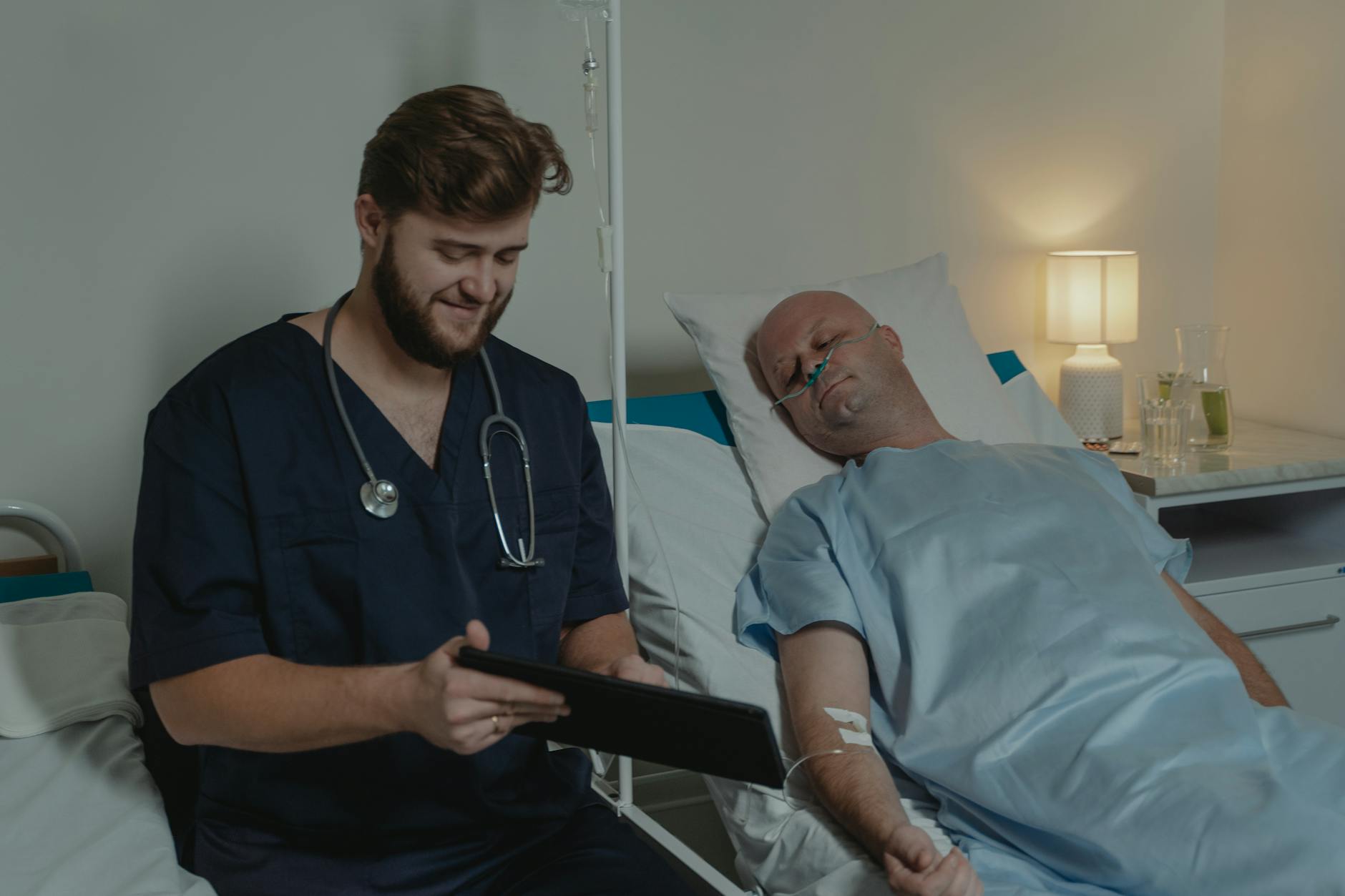 man wearing a blue scrub suit sitting beside a patient